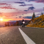 Motorcycle driver riding with light surrounded by mountains Motorcycle driver riding with light surrounded by mountains