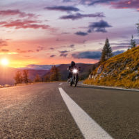 Motorcycle driver riding with light surrounded by mountains