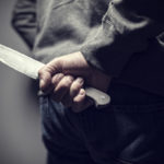 Person holding knife behind their back out of sight Person holding knife behind their back out of sight