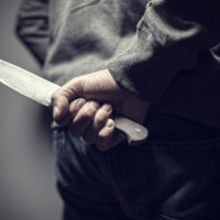 Person holding knife behind their back out of sight