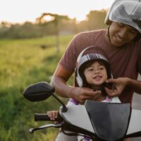 daddy help her daughter to fasten the helmet