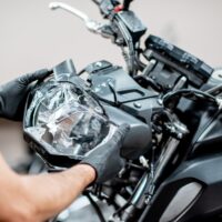 Worker repairing motorcycle headlight in the workshop