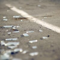 The shards of automotive glass in the accident, lying on the pavement about dividing the solid lines on the roadway