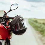 Black motorcycle helmet hanging on the handlebars of the motorcycle