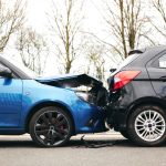 Two cars involved in traffic accident on side of the road with damage to bonnet and fender