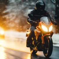 Motorcyclist rides on a motorbike on the snowy road in winter