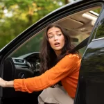 Scared shocked young woman having trouble on road, opening automobile door and looking back, having problem
